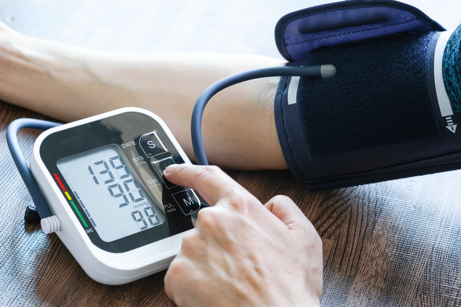 Tensiómetro digital midiendo la presión arterial en el brazo de una persona, con el manguito colocado